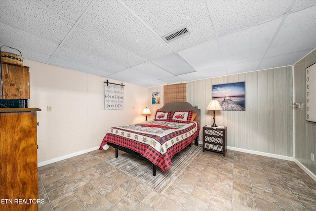 bedroom with a paneled ceiling and wooden walls