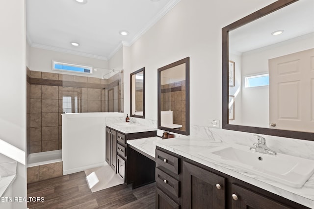 bathroom featuring tiled shower, wood-type flooring, vanity, and ornamental molding