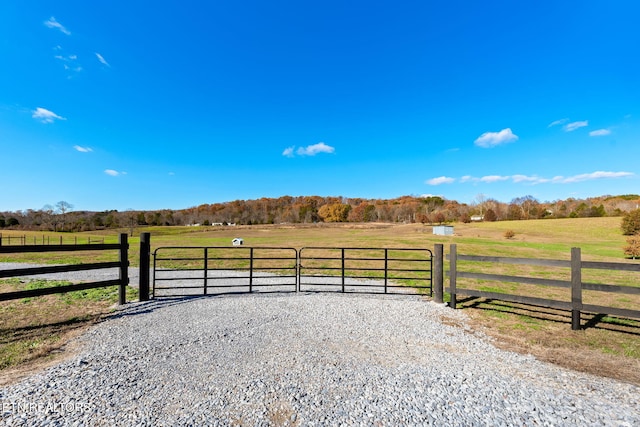 view of gate with a lawn and a rural view