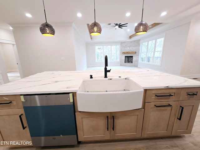 kitchen with a sink, light stone counters, recessed lighting, a stone fireplace, and dishwasher