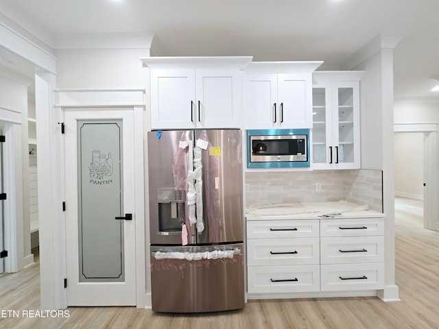 kitchen featuring backsplash, light wood-style flooring, appliances with stainless steel finishes, and light stone counters