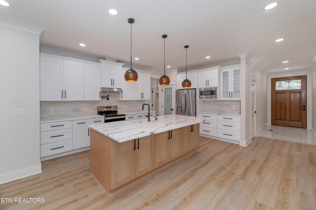 kitchen with a center island with sink, under cabinet range hood, a sink, stainless steel appliances, and light wood-style floors