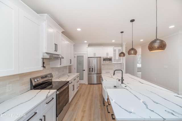 kitchen with under cabinet range hood, white cabinetry, appliances with stainless steel finishes, and a sink