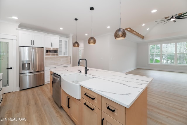 kitchen featuring a sink, stainless steel appliances, light wood-style floors, tasteful backsplash, and open floor plan