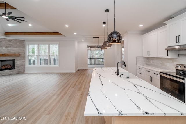 kitchen featuring a fireplace, decorative backsplash, electric stove, under cabinet range hood, and open floor plan