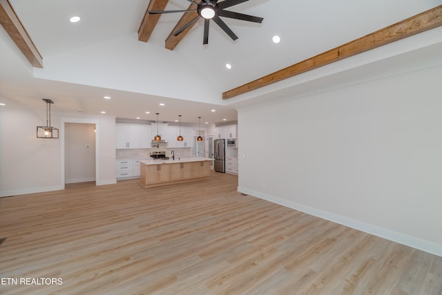 unfurnished living room featuring beamed ceiling, light wood-style flooring, high vaulted ceiling, and baseboards