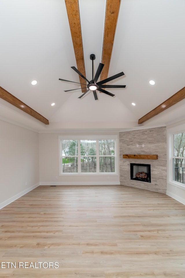 unfurnished living room featuring beamed ceiling, a large fireplace, and baseboards