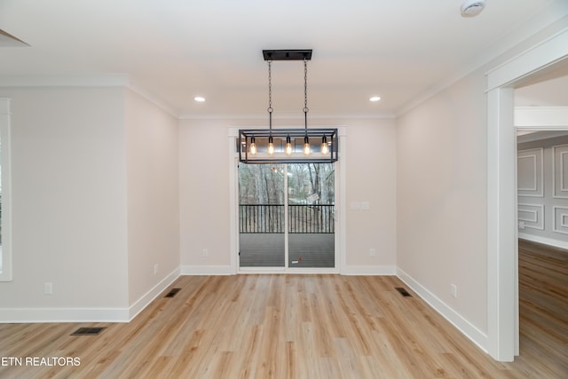 unfurnished dining area with light wood-type flooring, visible vents, baseboards, and crown molding