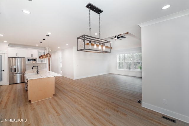 kitchen with a center island with sink, light wood-style floors, open floor plan, and stainless steel appliances