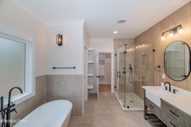 full bathroom featuring a freestanding tub, visible vents, a stall shower, tile walls, and a spacious closet