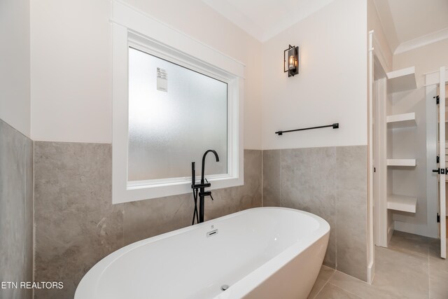 bathroom with tile patterned floors, a freestanding tub, tile walls, and wainscoting