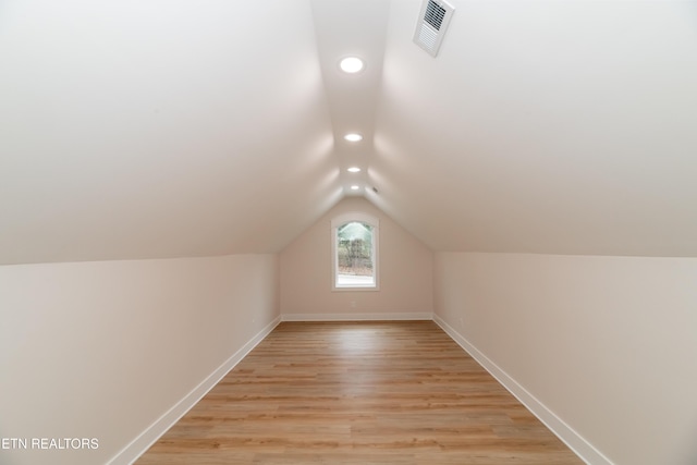 additional living space featuring lofted ceiling, baseboards, visible vents, and light wood-type flooring