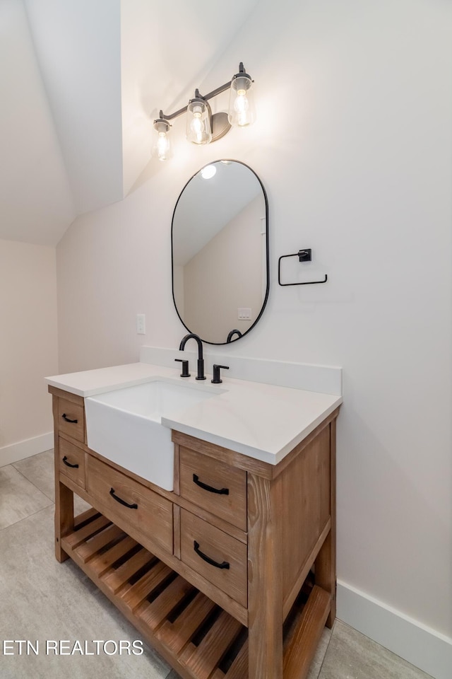 bathroom featuring baseboards, vanity, and lofted ceiling