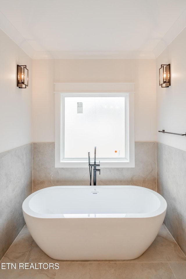 full bath with tile patterned floors, a healthy amount of sunlight, and a freestanding bath