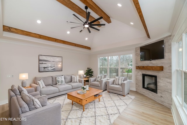 living area featuring beamed ceiling, light wood-type flooring, recessed lighting, a fireplace, and a ceiling fan