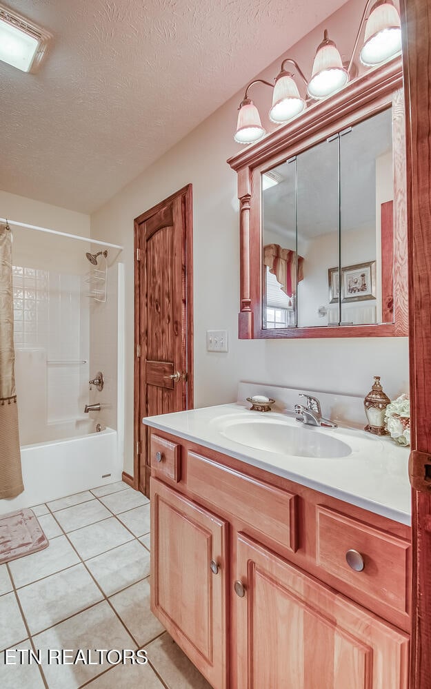 bathroom with tile patterned flooring, shower / tub combo, a textured ceiling, and vanity