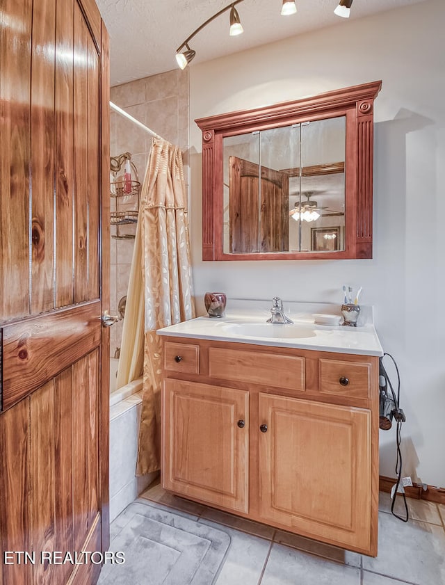 bathroom featuring tile patterned floors, vanity, a textured ceiling, shower / tub combo with curtain, and ceiling fan