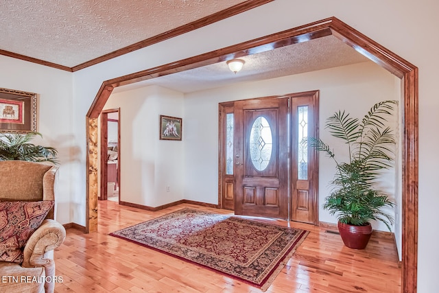 entryway featuring a textured ceiling, light hardwood / wood-style floors, and ornamental molding