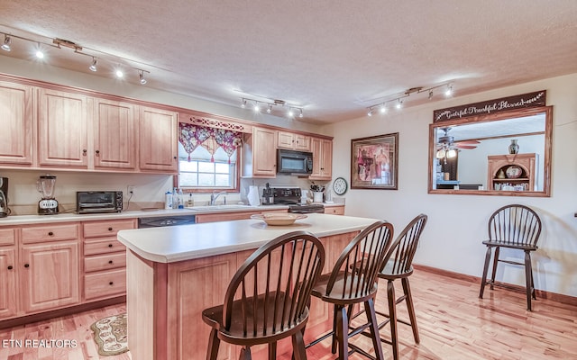 kitchen featuring black appliances, a center island, a textured ceiling, and track lighting