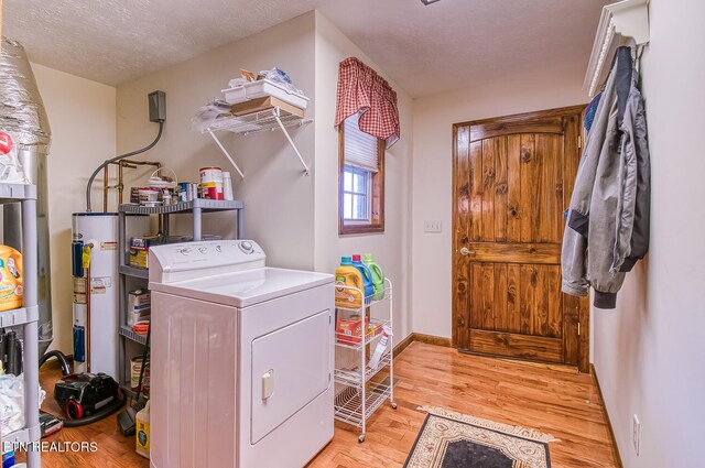 laundry room featuring washer / dryer, light wood-type flooring, a textured ceiling, and water heater