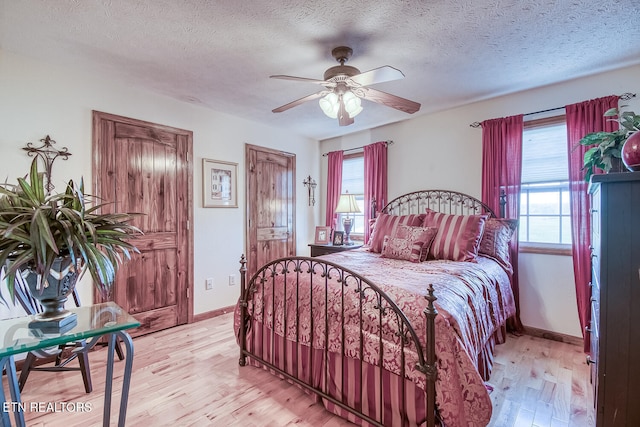 bedroom with a textured ceiling, light hardwood / wood-style flooring, multiple windows, and ceiling fan