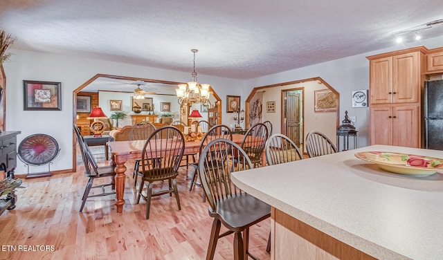 dining area featuring ceiling fan with notable chandelier, a textured ceiling, light hardwood / wood-style floors, and track lighting