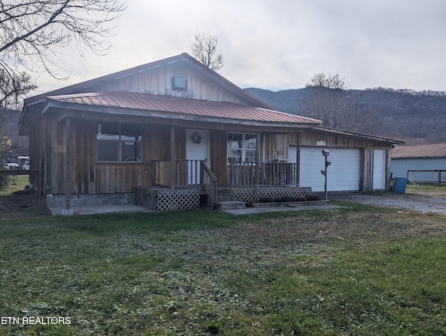 view of front of property featuring covered porch, a mountain view, a garage, and a front lawn