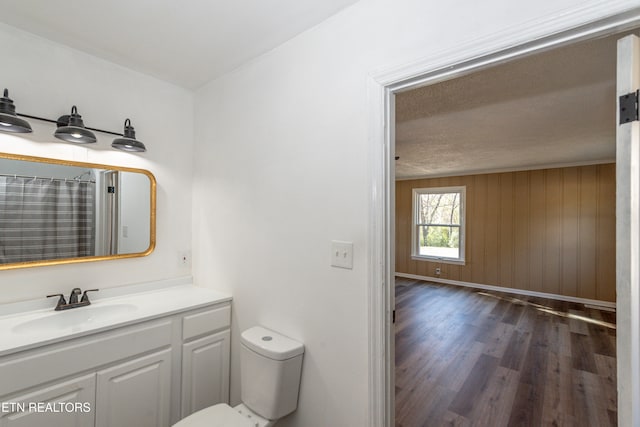 bathroom featuring toilet, wood-type flooring, wooden walls, vanity, and a shower with curtain