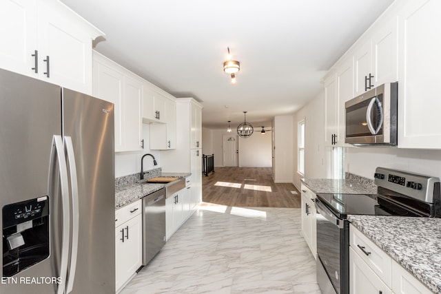 kitchen featuring white cabinetry, light stone counters, and appliances with stainless steel finishes