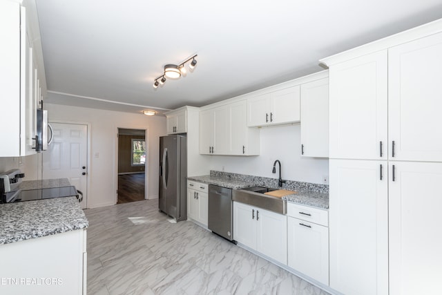 kitchen with light stone counters, white cabinets, appliances with stainless steel finishes, and sink