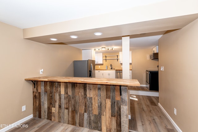 bar with sink, white cabinetry, stainless steel appliances, and hardwood / wood-style floors