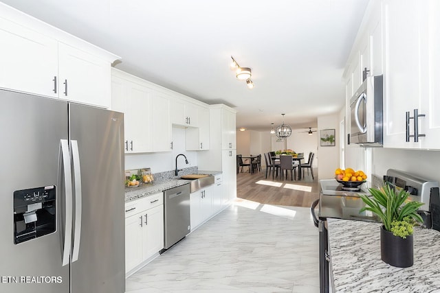 kitchen with sink, stainless steel appliances, white cabinetry, and light stone counters