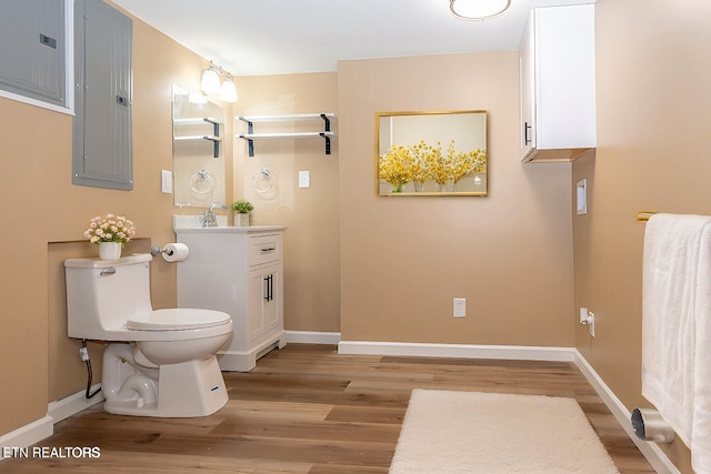 bathroom with hardwood / wood-style floors, electric panel, toilet, and vanity