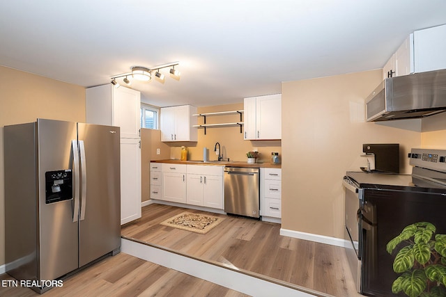 kitchen with light hardwood / wood-style floors, white cabinetry, sink, stainless steel appliances, and butcher block countertops