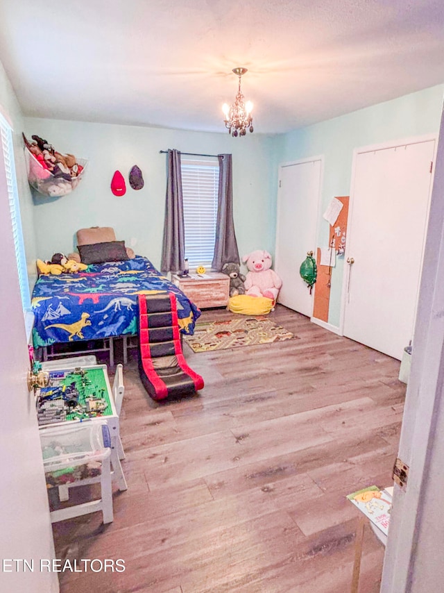 bedroom featuring multiple windows, a chandelier, and hardwood / wood-style floors