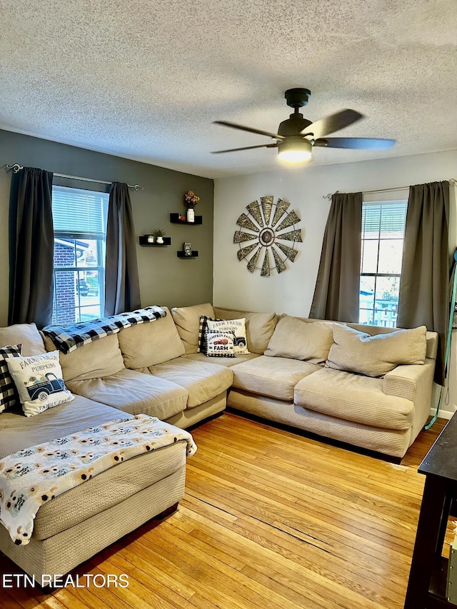 living room with wood-type flooring, a textured ceiling, and ceiling fan