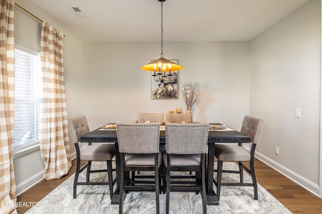 dining area featuring dark hardwood / wood-style flooring and an inviting chandelier