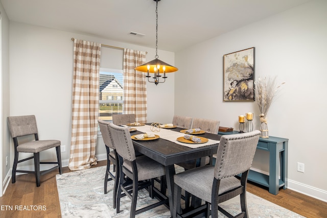 dining area with a notable chandelier and dark hardwood / wood-style flooring