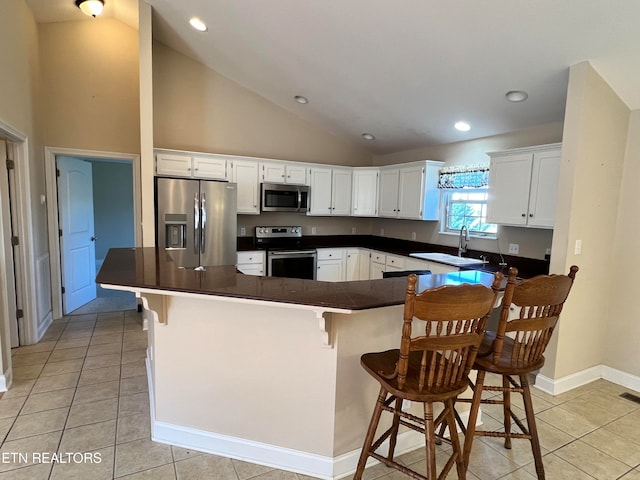 kitchen with a kitchen bar, stainless steel appliances, white cabinetry, and sink