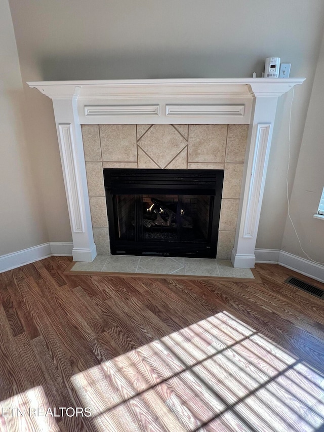 room details featuring a tiled fireplace and wood-type flooring