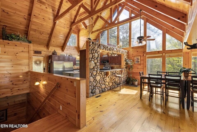 interior space featuring ceiling fan, wooden ceiling, light hardwood / wood-style flooring, beamed ceiling, and high vaulted ceiling