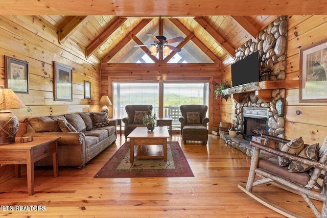 living room featuring a fireplace, beam ceiling, light wood-type flooring, and high vaulted ceiling