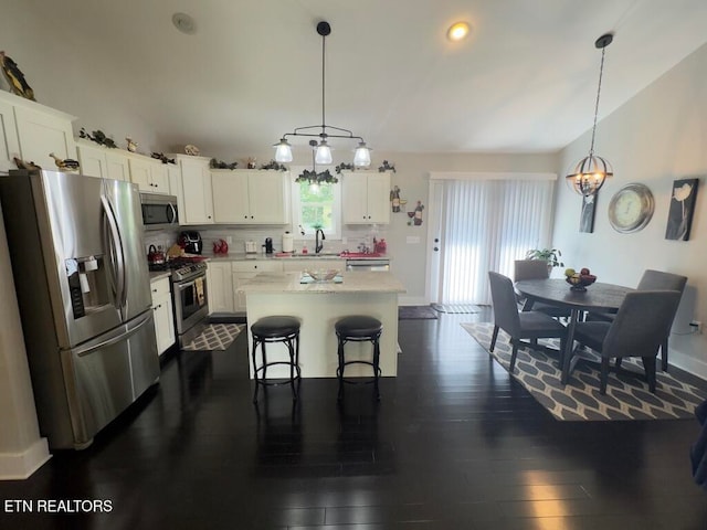 kitchen with pendant lighting, a kitchen island, white cabinets, and stainless steel appliances