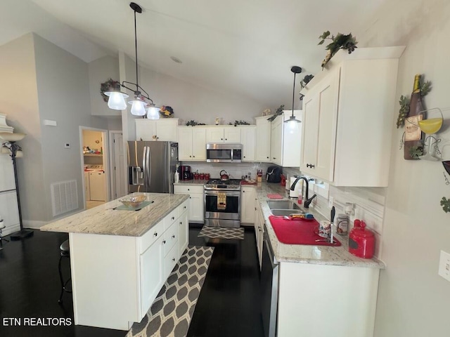 kitchen featuring appliances with stainless steel finishes, a center island, hanging light fixtures, and sink