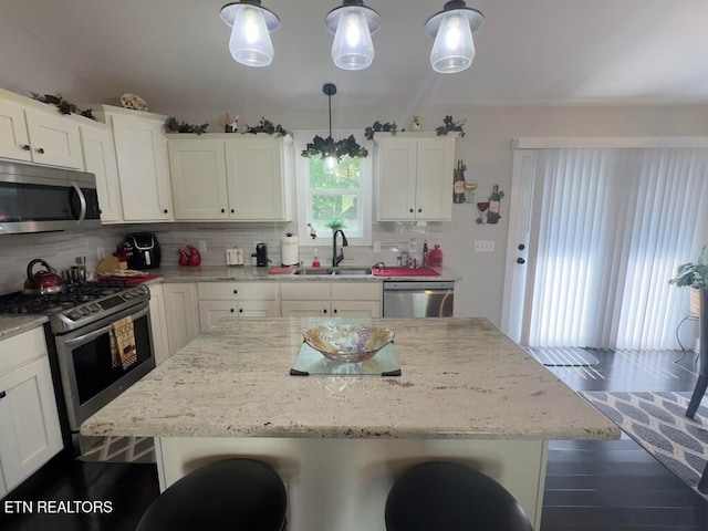 kitchen with sink, stainless steel appliances, tasteful backsplash, decorative light fixtures, and a breakfast bar area