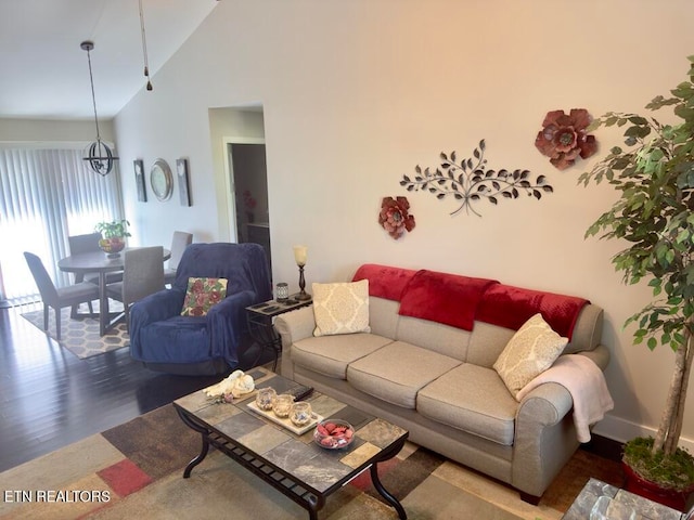 living room with an inviting chandelier, hardwood / wood-style flooring, and high vaulted ceiling