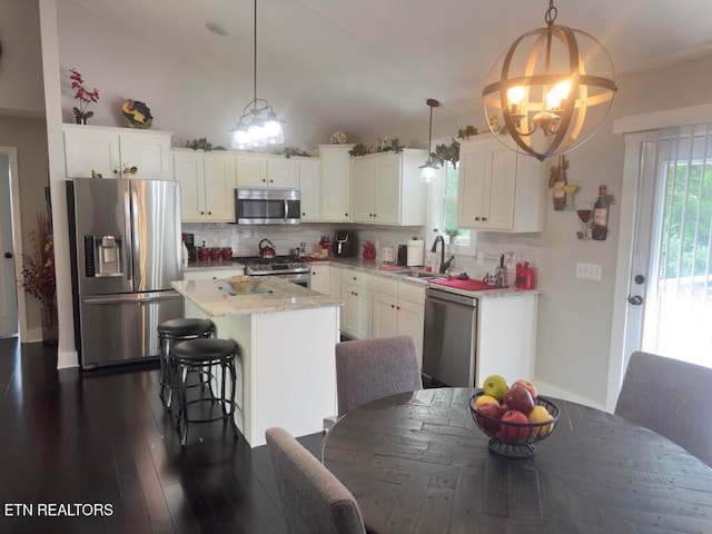 kitchen featuring a center island, sink, hanging light fixtures, white cabinetry, and stainless steel appliances