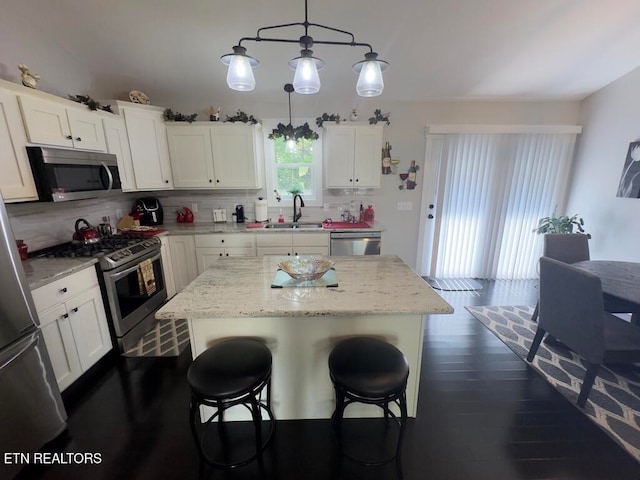 kitchen featuring white cabinetry, a kitchen island, stainless steel appliances, and decorative light fixtures