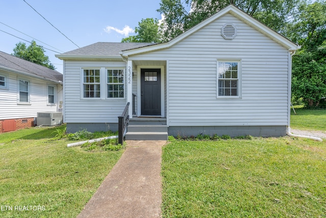 bungalow-style house with central air condition unit and a front lawn