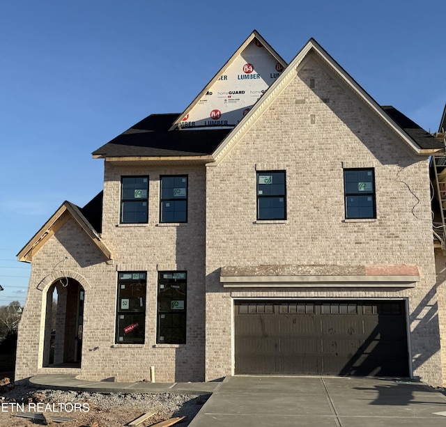 view of front of house with a garage, concrete driveway, and brick siding